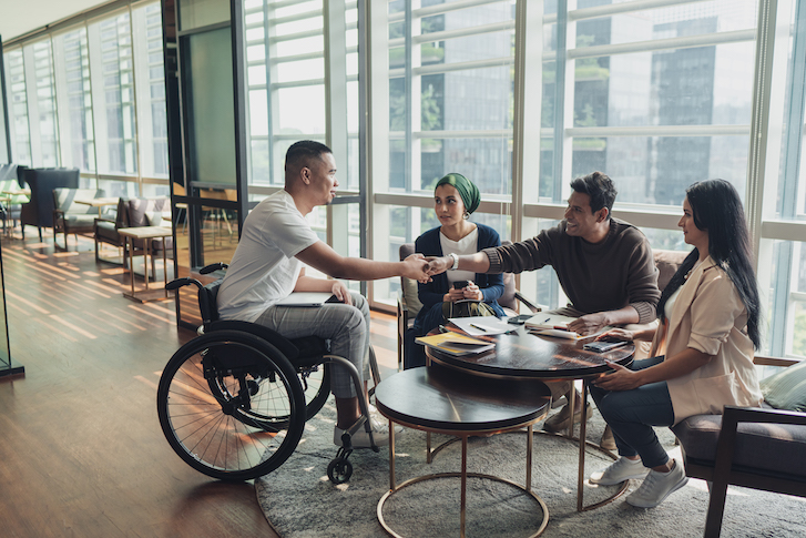 People sitting around table shaking hands